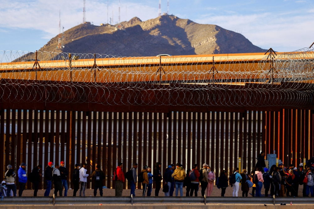 Migrants queue near the border fence, after crossing the Rio Bravo river, to request asylum in El Paso, Texas as seen from Ciudad Juarez, Mexico. — Reuters pic