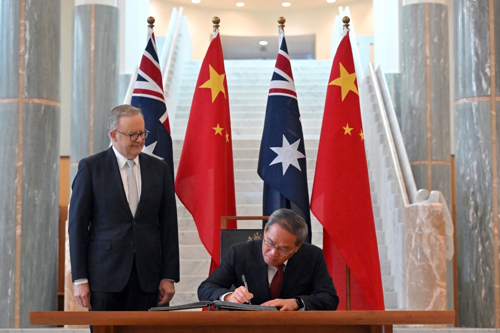 Chinese Premier Li Qiang signs the visitor book as Australia’s Prime Minister Anthony Albanese looks on at the Australian Parliament House in Canberra. — Reuters pic