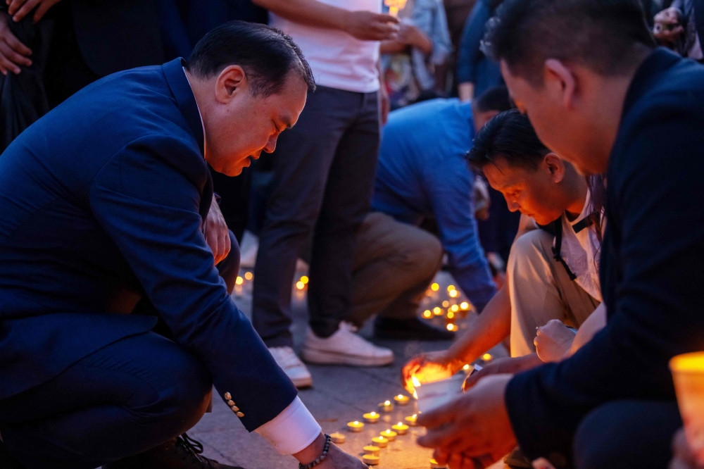 This photo taken on June 16, 2024 shows Mongolia’s Democratic Party leader L. Gantumor (left) lighting candles at Sukhbaatar Square in Ulaanbaatar, after a Mongolian opposition politician was beaten to death ahead of the country’s parliamentary elections. — AFP pic