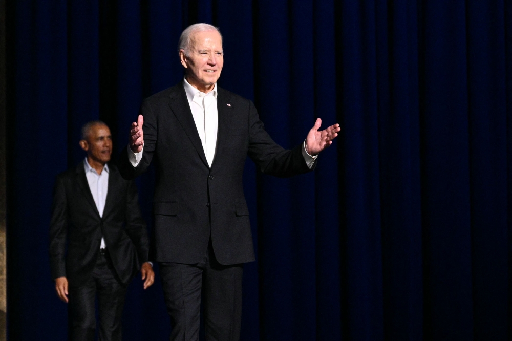 US President Joe Biden (right) gestures as he arrives onstage with former president Barack Obama during a campaign fundraiser at the Peacock Theater in Los Angeles June 15, 2024. ― AFP pic