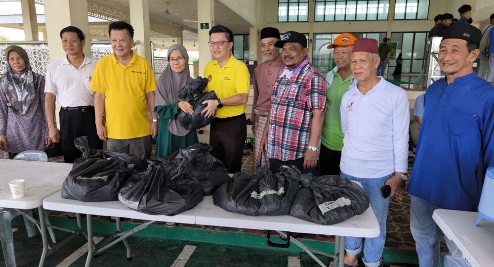 Chieng (fifth left) hands over the ‘korban’ meat to a villager, as Buong Toon (third left), Mohd Ali (sixth left) and others look on. — The Borneo Post pic