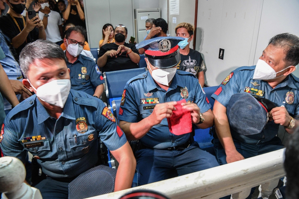 Four policemen attend their trial at a court in Manila on June 18, 2024. ― AFP pic