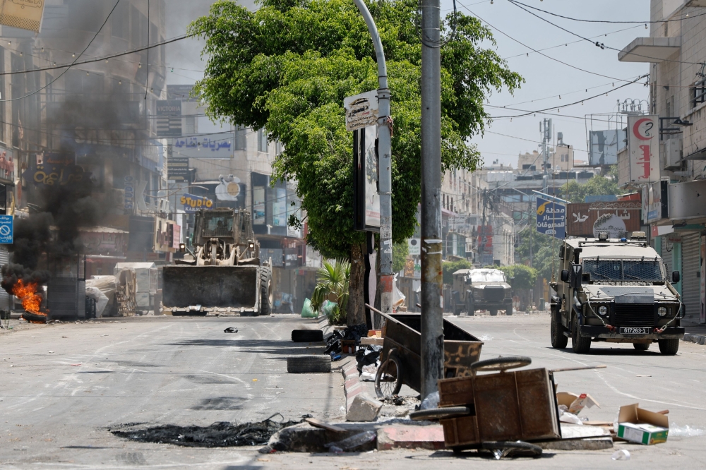 Military vehicles operate near a fire during an Israeli raid in Jenin, in the Israeli-occupied West Bank June 13, 2024. — Reuters pic