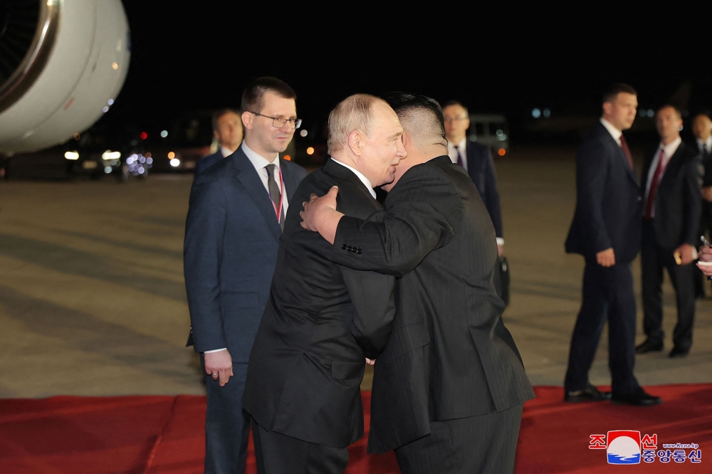 This picture taken early on June 19, 2024 and released from North Korea's official Korean Central News Agency (KCNA) via KNS shows North Korea's leader Kim Jong-un welcoming Russia's President Vladimir Putin upon his arrival at Pyongyang International Airport in the North Korean capital. — KCNA VIA KNS / AFP pic