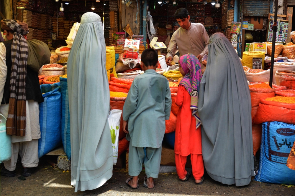 Afghan burqa-clad women buy dry fruits at a market in Kandahar on June 15, 2024, on the eve of the Muslim festival of Eid al-Adha. — AFP pic