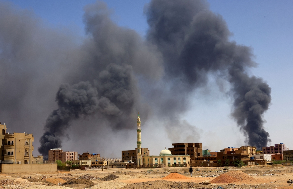 A man walks while smoke rises above buildings after aerial bombardment, during clashes between the paramilitary Rapid Support Forces and the army in Khartoum North, Sudan, May 1, 2023. — Reuters pic