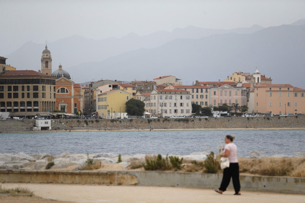 A woman walks along the seafront in Ajaccio, on the French Mediterranean island of Corsica, on June 20, 2024, after an alert of atmospheric pollution was activated due to Sahara particules in the air. — AFP pic