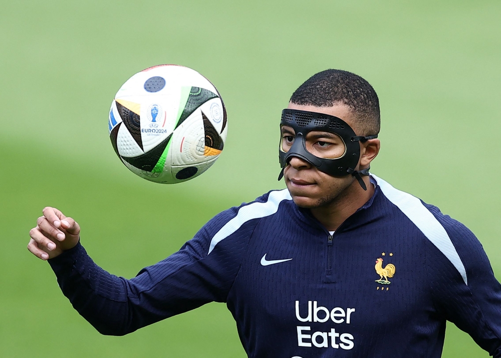 France's forward Kylian Mbappe, wearing a protective mask, eyes the ball during a training session  training session at the Home Deluxe Arena Stadium in Paderborn, western Germany June 23, 2024. — AFP pic