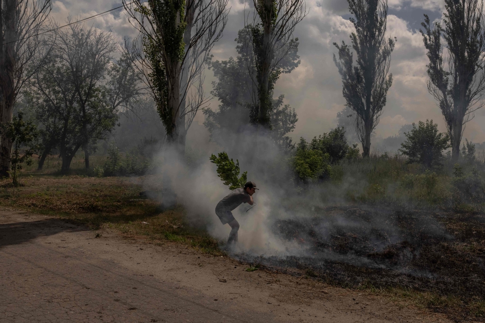 A man tries to stop a fire following shelling in Druzhkivka, eastern Donetsk region, on June 24, 2024, amid the Russian invasion of Ukraine. — AFP pic