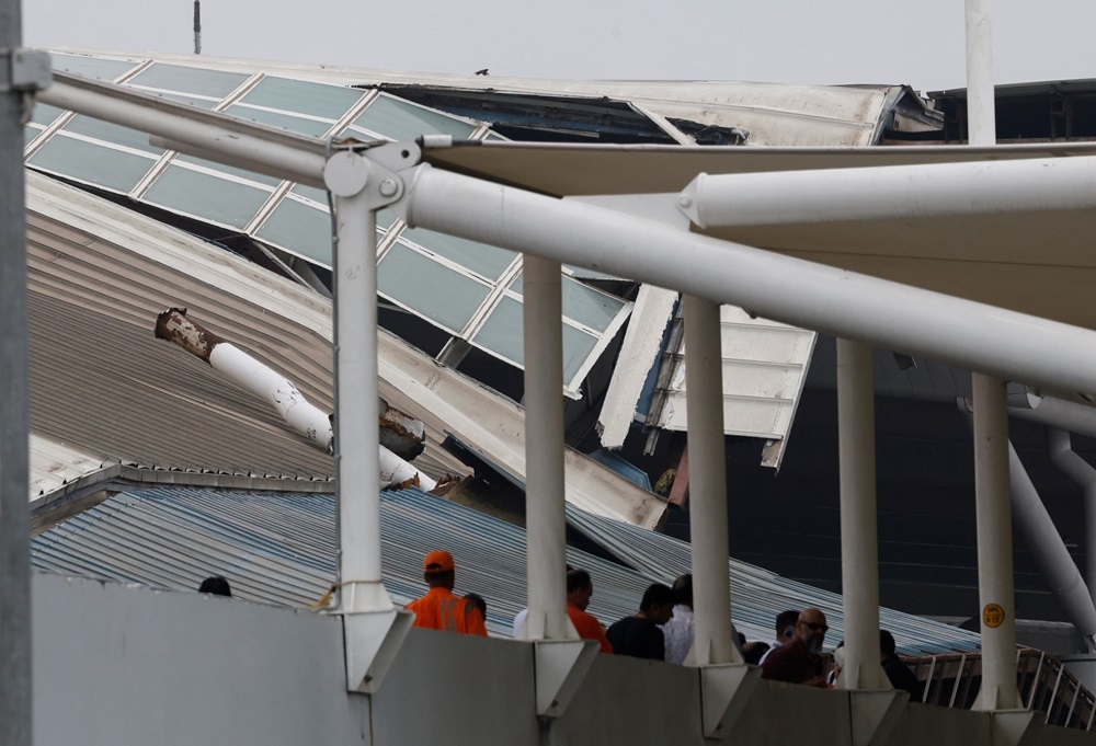 People stand in front of the portion of a damaged canopy at Terminal 1 following heavy rainfall at the Indira Gandhi International Airport in New Delhi June 28, 2024. — Reuters pic 
