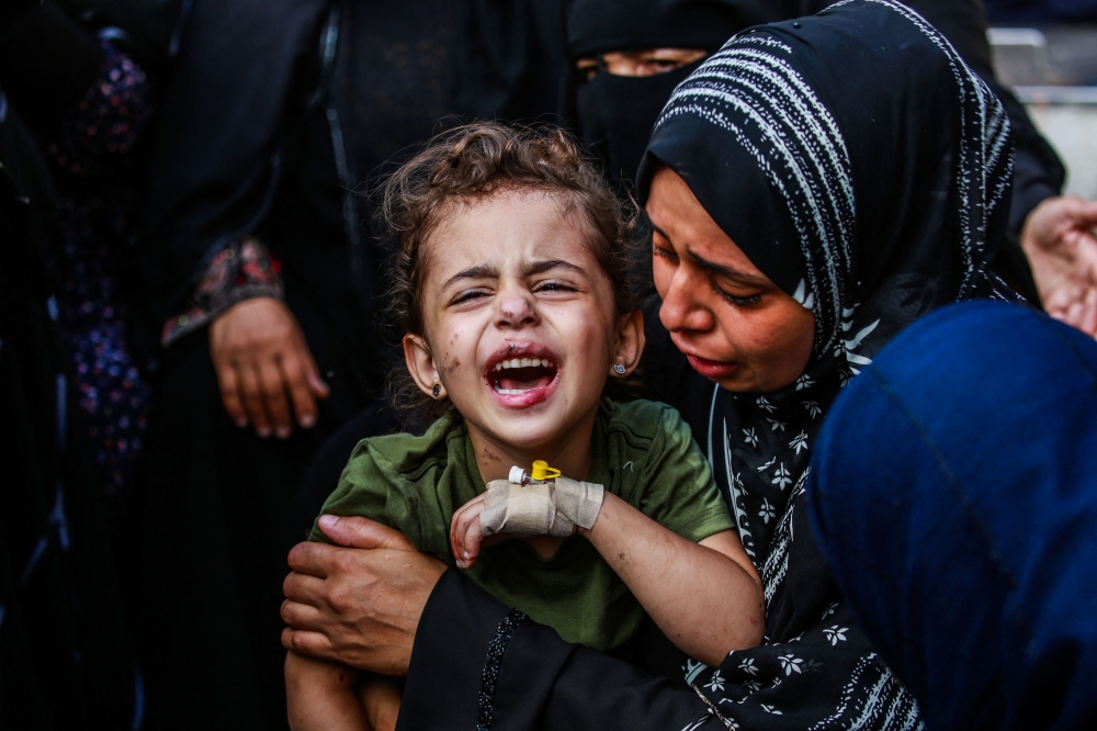 An injured girl is comforted by her relatives at the Aqsa Martyrs Hospital in Deir el-Balah June 25, 2024, following Israeli bombardments in the central Gaza Strip amid ongoing battles between Israel and the Palestinian group Hamas. — AFP pic