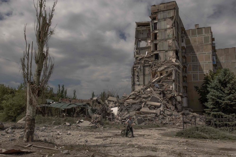 File photo of a local resident pushing a bicycle past a destroyed residential building following shelling in the town of Toretsk, eastern Donetsk region, on June 25, 2024, amid the Russian invasion of Ukraine. — AFP pic