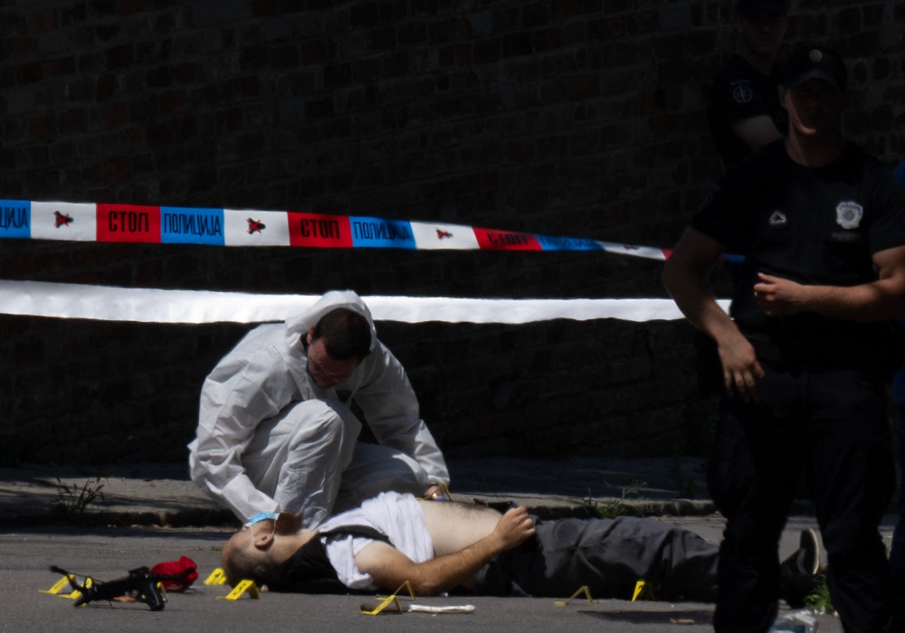 A forensic police officer inspects a body lying on the road next to the Israeli embassy in Belgrade, Serbia, on June 29, 2024. — AFP pic