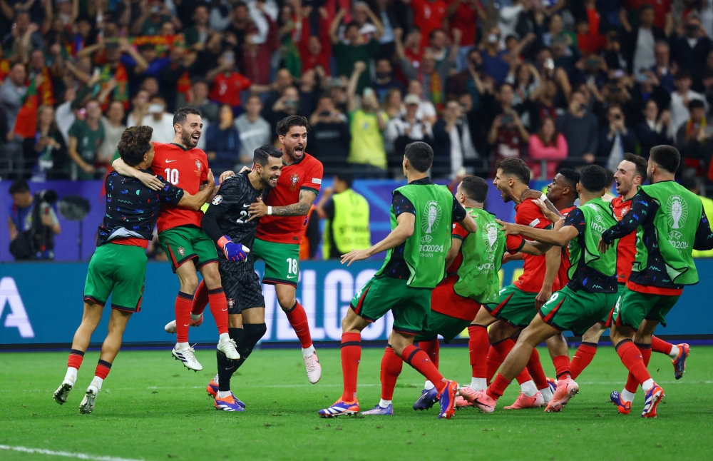 Portugal's Diogo Costa with teammates celebrate after winning the penalty shoot-out. —Reuters pic