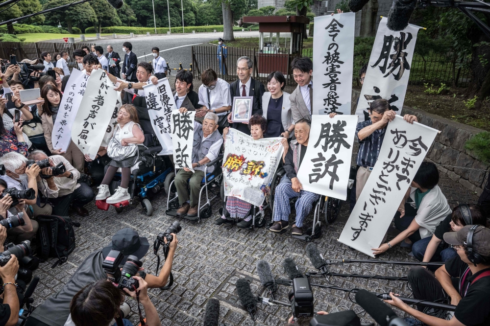 Victims of forced sterilisation under a now-defunct eugenics law, celebrate with lawyers and supporters outside of the Supreme Court of Japan in Tokyo July 3, 2024. — AFP pic