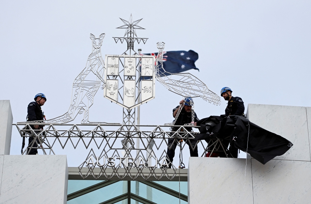 Australian Federal Police officers remove a pro-Palestinian protest banner from the forecourt of the Australian Parliament House, in Canberra, Australia, July 4, 2024. — Reuters pic