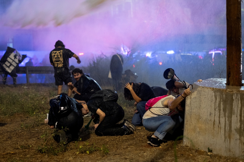 People take cover as police use water cannon during a demonstration against Netanyahu's government and a call for the release of hostages in Gaza, amid the Israel-Hamas conflict, in Tel Aviv, Israel. —Reuters pic