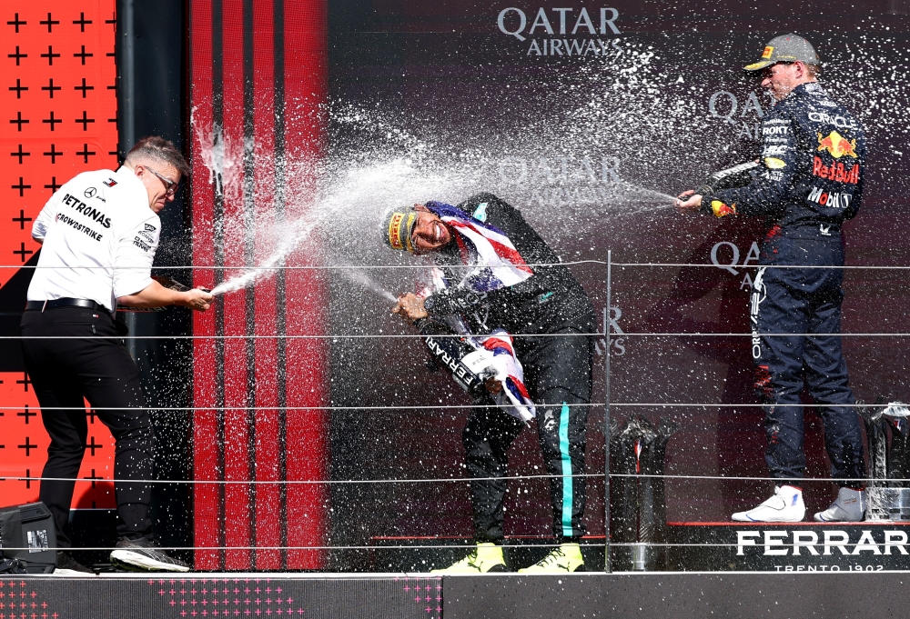 Hamilton celebrates on the podium with champagne after winning the British Grand Prix with senior race engineer Peter Bonnington and second-placed Verstappen. —Reuters