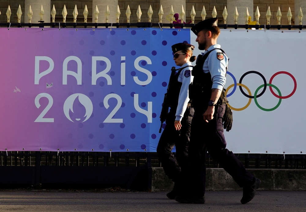 French gendarmes patrol a street near a poster advertising the Paris 2024 Summer Games in Paris, France last month. — Reuters pic