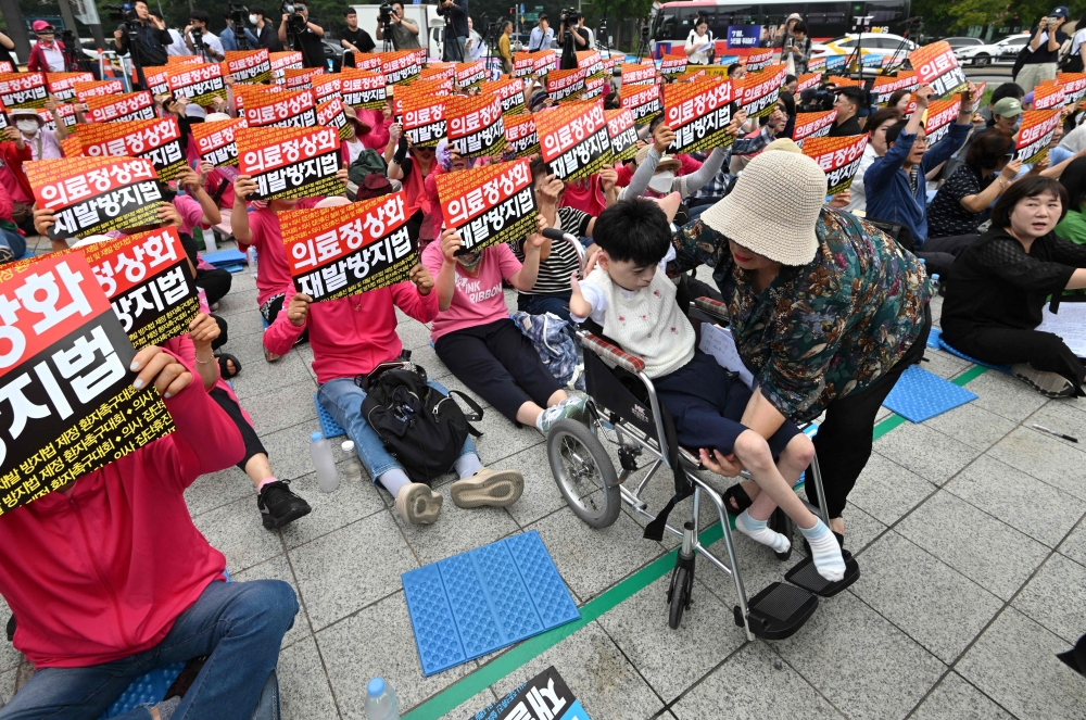 Park Ha-eun (on wheelchair), a 23-year-old South Korean patient with Cornelia de Lange syndrome, and her mother Kim Jeong-ae (R) attend a rally against doctors' strike in Seoul on July 4, 2024. — AFP pic