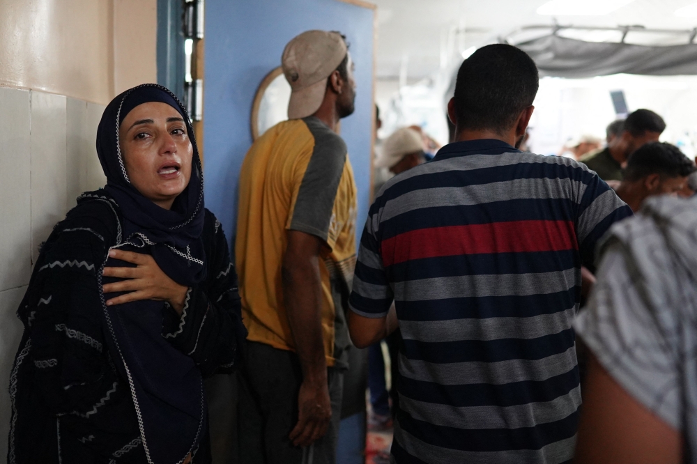 A weeping woman stands at the entrance of the emergency ward at Nasser hospital in Khan Yunis as victims are brought in from a nearby area targeted by Israeli strikes in the southern Gaza Strip on July 9, 2024, amid the ongoing conflict between Israel and the Palestinian militant group Hamas. A deadly strike hit a school turned shelter in southern Gaza on July 9 as Israeli forces in the war-ravaged territory's main city pushed on with a major offensive that has again displaced Palestinians. A hospital source in Khan Yunis said at least 29 people were killed when the Al-Awda school was hit in nearby Abasan while the Israeli military said its air force had carried out a strike in the area targeting a 