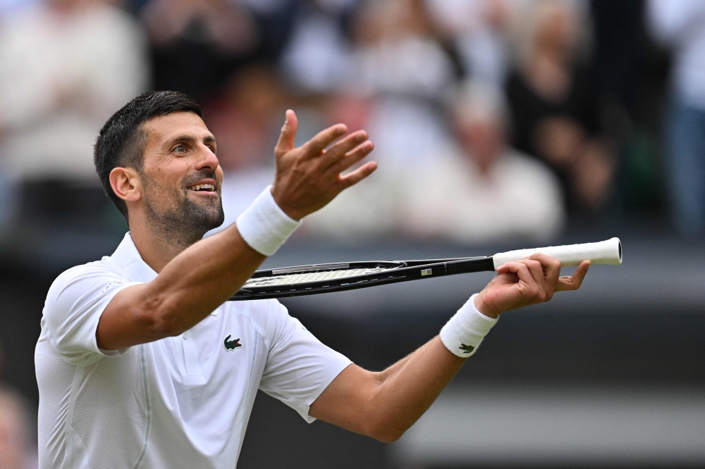 Serbia's Novak Djokovic imitates playing the violin with his racquet as he celebrates winning against Italy's Lorenzo Musetti during their men's singles semi-final tennis match on the twelfth day of the 2024 Wimbledon Championships at The All England Lawn Tennis and Croquet Club in Wimbledon July 12, 2024. — AFP pic