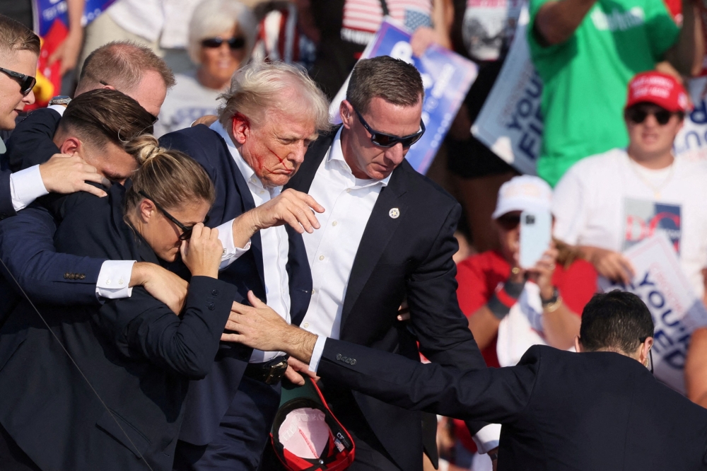 As the shots rang out, former US President Donald Trump grabbed his right ear with his right hand, then brought his hand down to look at it before dropping to his knees behind the podium before Secret Service agents swarmed and covered him. — Reuters pic