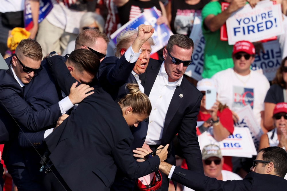 Republican presidential candidate and former US President Donald Trump is assisted by US Secret Service personnel after gunfire rang out during a campaign rally at the Butler Farm Show in Butler, Pennsylvania, July 14, 2024. — Reuters pic