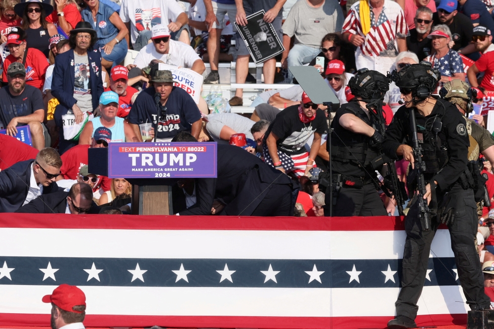 Republican presidential candidate and former US President Donald Trump is assisted by US Secret Service personnel after gunfire rang out during a campaign rally at the Butler Farm Show in Butler, Pennsylvania July 13, 2024. — Reuters pic