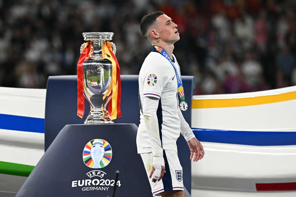 England’s midfielder #11 Phil Foden walks with his silver medal past to the trophy after the Uefa Euro 2024 final football match between Spain and England at the Olympiastadion in Berlin July 14, 2024. — AFP pic