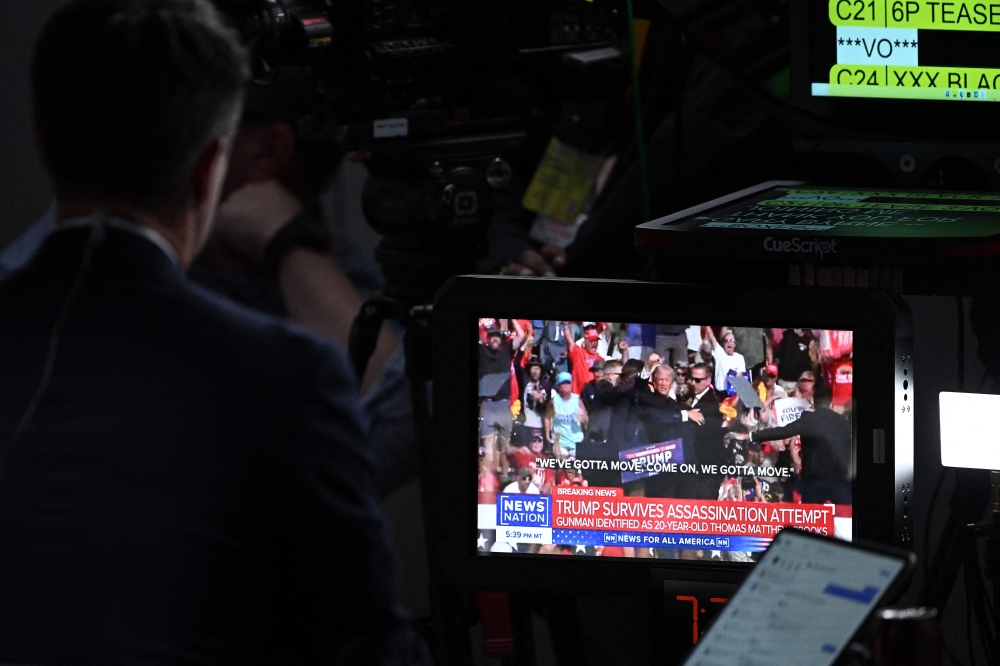 A TV screen displays news on the failed assassination attempt on former US president Donald Trump ahead of his formal nomination as the Republican candidate in the next US election. — AFP pic
