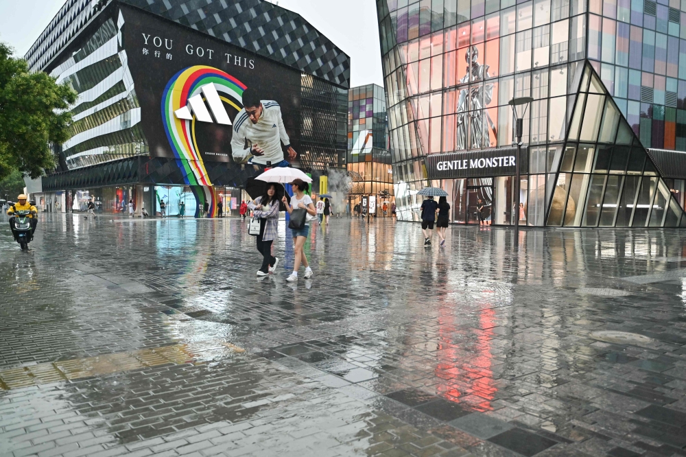 People use umbrellas to shelter from heavy rain in Beijing on July 12, 2024. China’s economy dipped to 4.7 per cent in the second quarter of 2024 compared to 5.3 per cent in the first quarter. — AFP pic