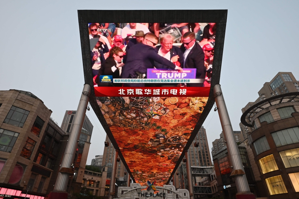 A news programme about the assassination attempt on former US president Donald Trump is seen on a giant screen at a shopping mall in Beijing, China on July 14, 2024. — AFP pic