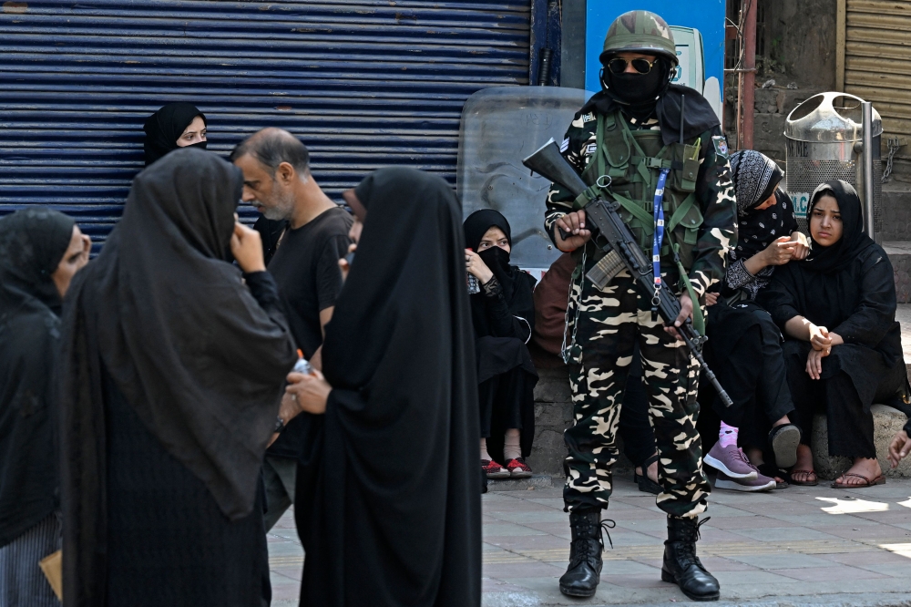 An Indian soldier watches as Kashmiri Shiite women take part in a Muharram procession on the eighth day of Ashura in Srinagar on July 15, 2024, after the state government allowed the parade for the second time in three decades. — AFP pic