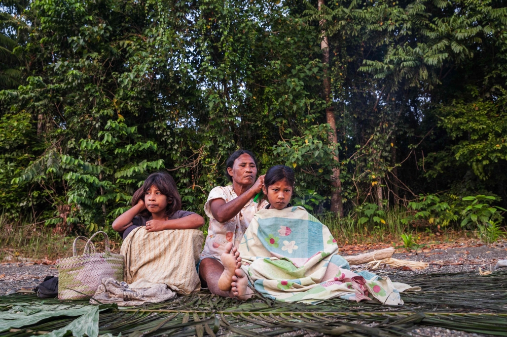 This photo taken on October 5, 2014 shows a family from the O'Hongana Manyawa (Tobelo) tribe resting on the riverbank after spending the night on the Halmahera island, North Maluku. Deforestation at one of Indonesia's largest nickel processing hubs is threatening an Indigenous group that is among the country's last uncontacted tribes, rights groups allege. — AFP pic