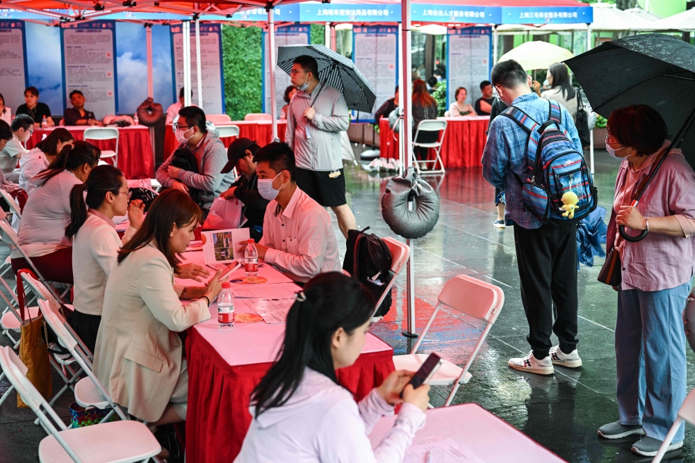People visit a job fair in in Shanghai May 31, 2024. At a job fair for soon-to-be graduates in central Shanghai on May 31, recruiters sat bored under washed-out tarpaulins as rain and an apparent lack of interest kept potential young employees away. — AFP pic