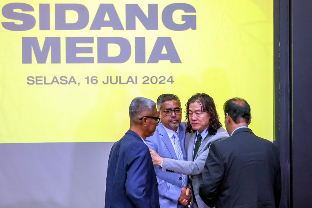 Harimau Malaya Head Coach Kim Pan Gon (2nd right) is hugged by FAM secretary-general Noor Zaman Rahman (2nd left) after the press conference announcing his resignation as head coach of the national squad at Wisma FAM in Petaling Jaya July 16, 2024. — Bernama pic