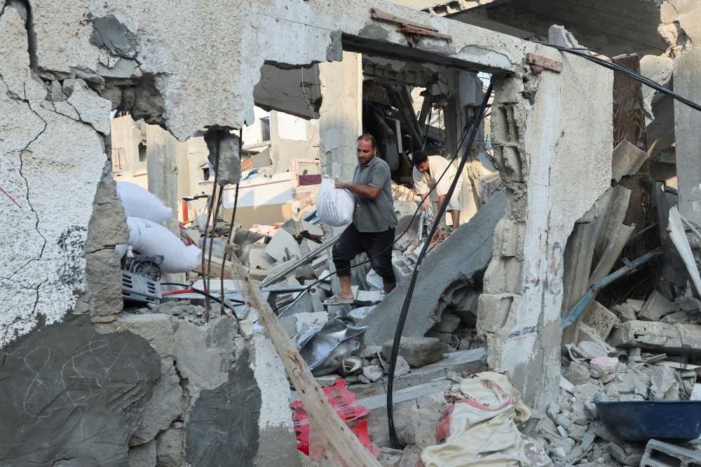 A Palestinian man carries a sack at the site of an Israeli strike on a house, amid the Israel-Hamas conflict, in the central Gaza Strip, July 16, 2024. — Reuters pic