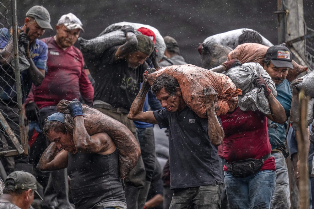 Emerald seekers carry sacks of soil already discarded by the multinational Esmeraldas Mining Services (EMS) to search for green gems at the Las Animas River in Muzo, Boyaca Department, Colombia, on June 19, 2024. — AFP pic 
