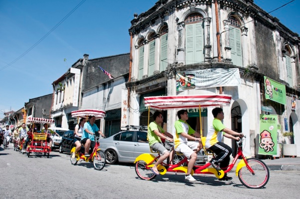 Tourists are seen riding rented tandem bicycles with canopies around George Town’s heritage area. — Picture by K.E. Ooi
