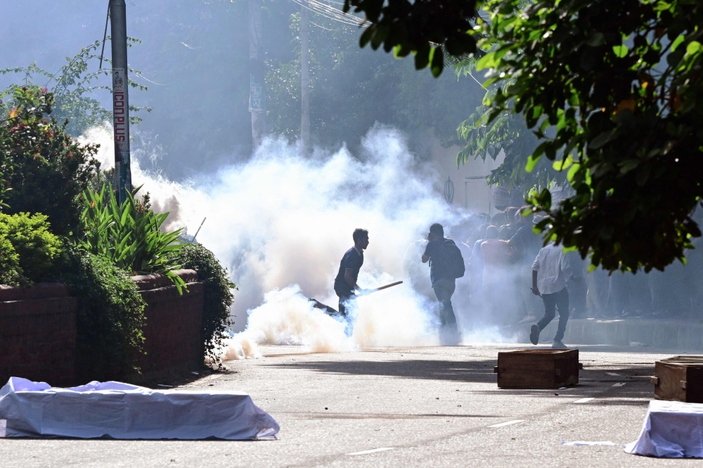 Bangladesh police personnel fire tear shells as students protest against quotas in government jobs alongside symbolic coffins of victims who died in a clash with the police,  during their absentee funeral prayer ceremony at Dhaka University in the capital on July 17, 2024. — AFP pic