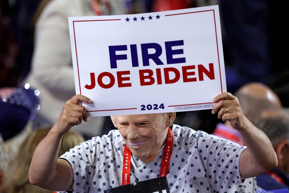 An attendee wearing a US President Joe Biden mask holds a sign during the last day of the 2024 Republican National Convention at the Fiserv Forum in Milwaukee, Wisconsin July 18, 2024. — AFP pic