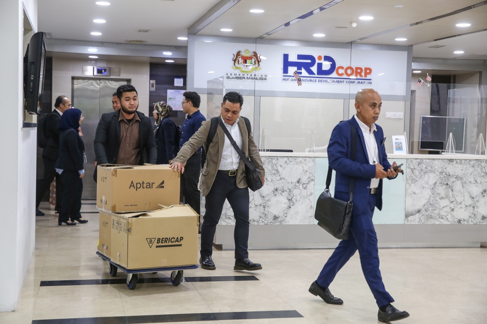 Anti-corruption investigators escort documents taken from the Human Resource Development Corporation (HRD Corp) office in Kuala Lumpur on July 9, 2024. — Picture by Yusof Mat Isa