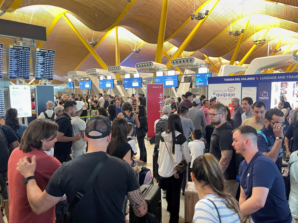 Passengers wait at Barajas Airport, as Spanish airport operator Aena today reported a computer systems ‘incident’ at all Spanish airports which may cause flight delays. — Reuters pic