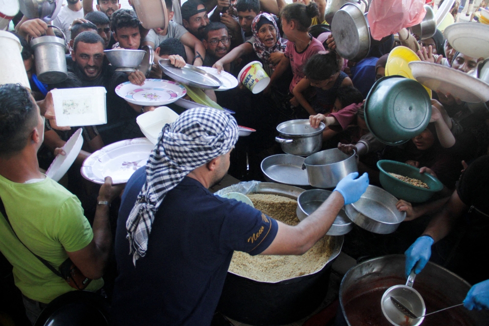 Palestinian children gather to receive food cooked by a charity kitchen, amid food scarcity, as Israel-Hamas conflict continues, in the northern Gaza Strip, July 18, 2024. — Reuters pic