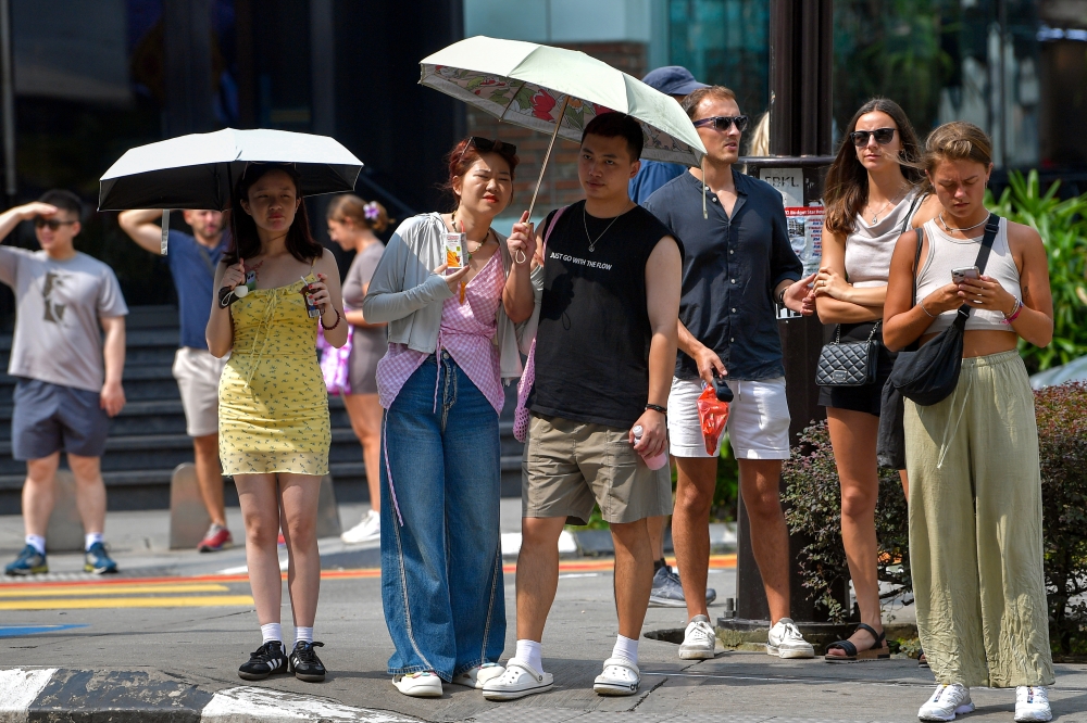 A file photograph shows people sheltering under umbrellas in Kuala Lumpur. — Bernama pic