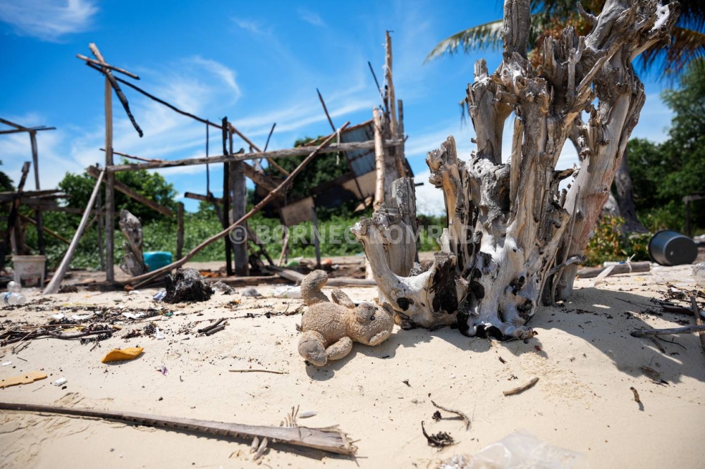 A burnt teddy bear belonging to a Bajau Laut child in front of the remains of a family home. — Picture courtesy of Borneo Komrad