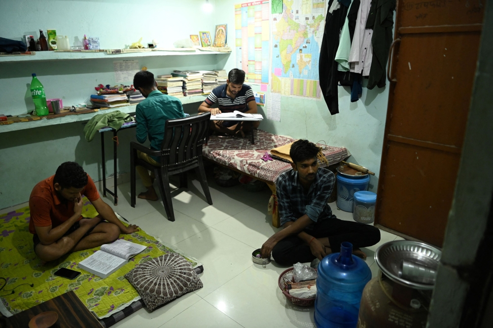 Government job aspirants Pradeep Kumar Gupta, 22, Rai Pal Singh, 18, and Shubham Pandey, 19, study in their room, while Ankit Pal, 19, prepares lunch at a student's lodge in Prayagraj, Uttar Pradesh, India, June 21, 2024. Aspirants like Gupta and his friends often share their rooms to reduce expenses as they prepare for competitive exams to secure government jobs. — Reuters pic  