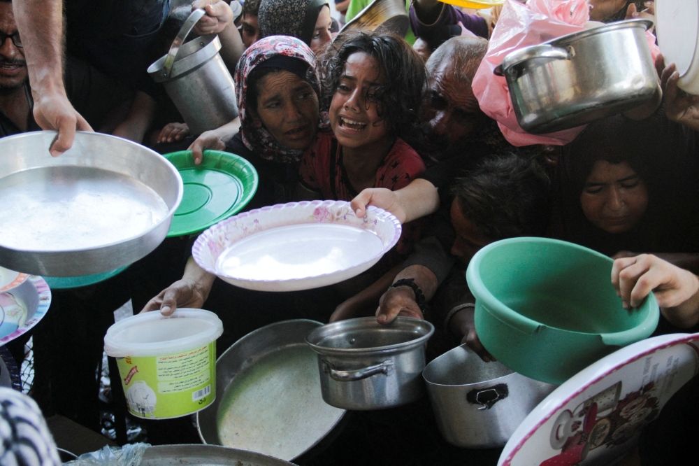 Palestinian children gather to receive food cooked by a charity kitchen, amid food scarcity, as Israel-Hamas conflict continues, in the northern Gaza Strip, July 18, 2024. — Reuters pic