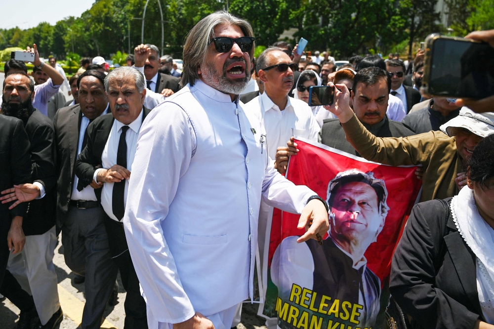 Parliamentarians of the Pakistan Tehreek-e-Insaf (PTI) party, carry posters of jailed former prime minister Imran Khan, during a protest outside the Parliament house in Islamabad on July 18, 2024. — AFP pic